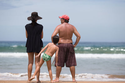 Rear view of men standing on beach