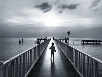 Rear view of man standing on jetty against sea