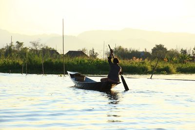 Man in boat on lake against sky