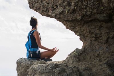 Side view of woman sitting on rock