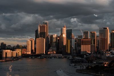 City at waterfront against cloudy sky