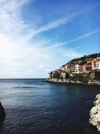 Scenic view of sea by buildings against sky