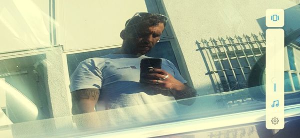 Reflection of man using mobile phone in mirror