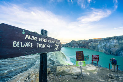 Information sign by mountain against sky