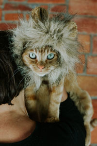 Cropped image of woman carrying cat against brick wall