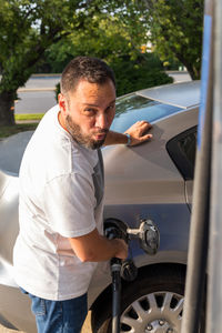 Side view of young man holding car