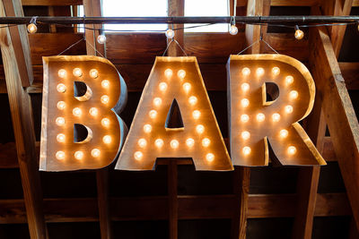 Low angle view of illuminated bar sign hanging on ceiling