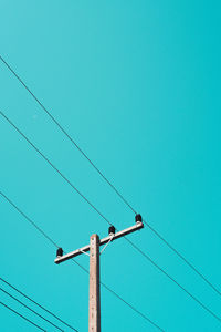 Low angle view of electricity pylon against blue sky