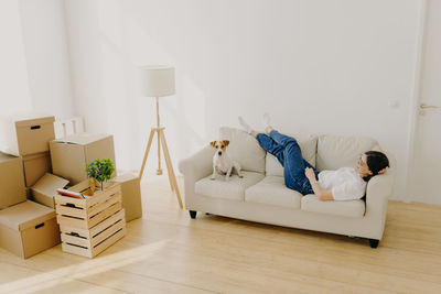 High angle view of woman relaxing on sofa with dog at home