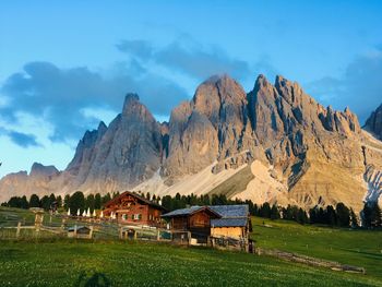 Built structure on field by mountains against sky ad the sunset