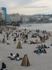 People at beach against sky in city