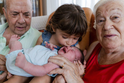 Grandparents with little girl and newborn baby at home