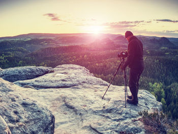 Photographer prepare camera to takes impressive photos of land. sharp rocky edge on high view point