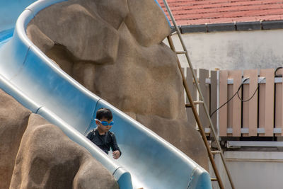 Boy sitting on slide in water park