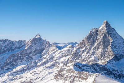 Scenic view of snowcapped mountains against clear blue sky