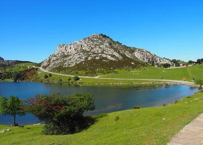 Scenic view of lake and mountains against clear blue sky