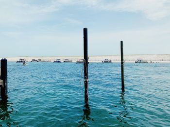 Wooden posts in sea against sky