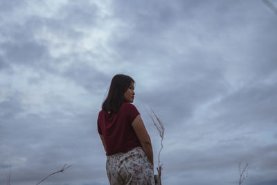 Low angle view of woman looking away against sky