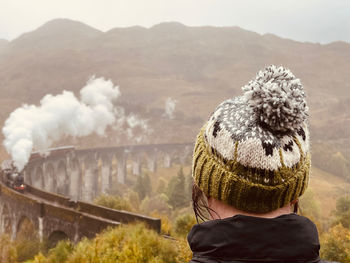 Rear view of woman standing against mountain