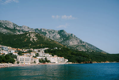 Scenic view of sea by townscape against sky