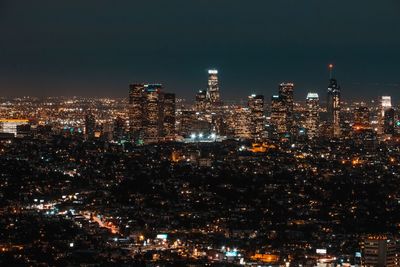 Illuminated cityscape against sky at night