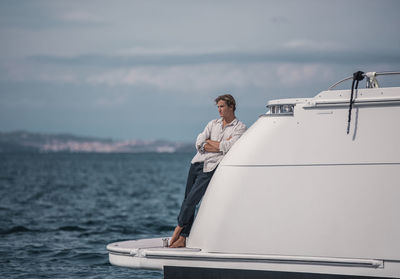 Man standing on boat in sea against sky