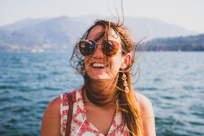 Portrait of woman wearing sunglasses against sea