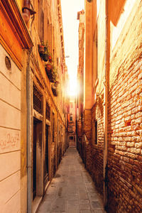 Walkway amidst buildings against sky during sunset