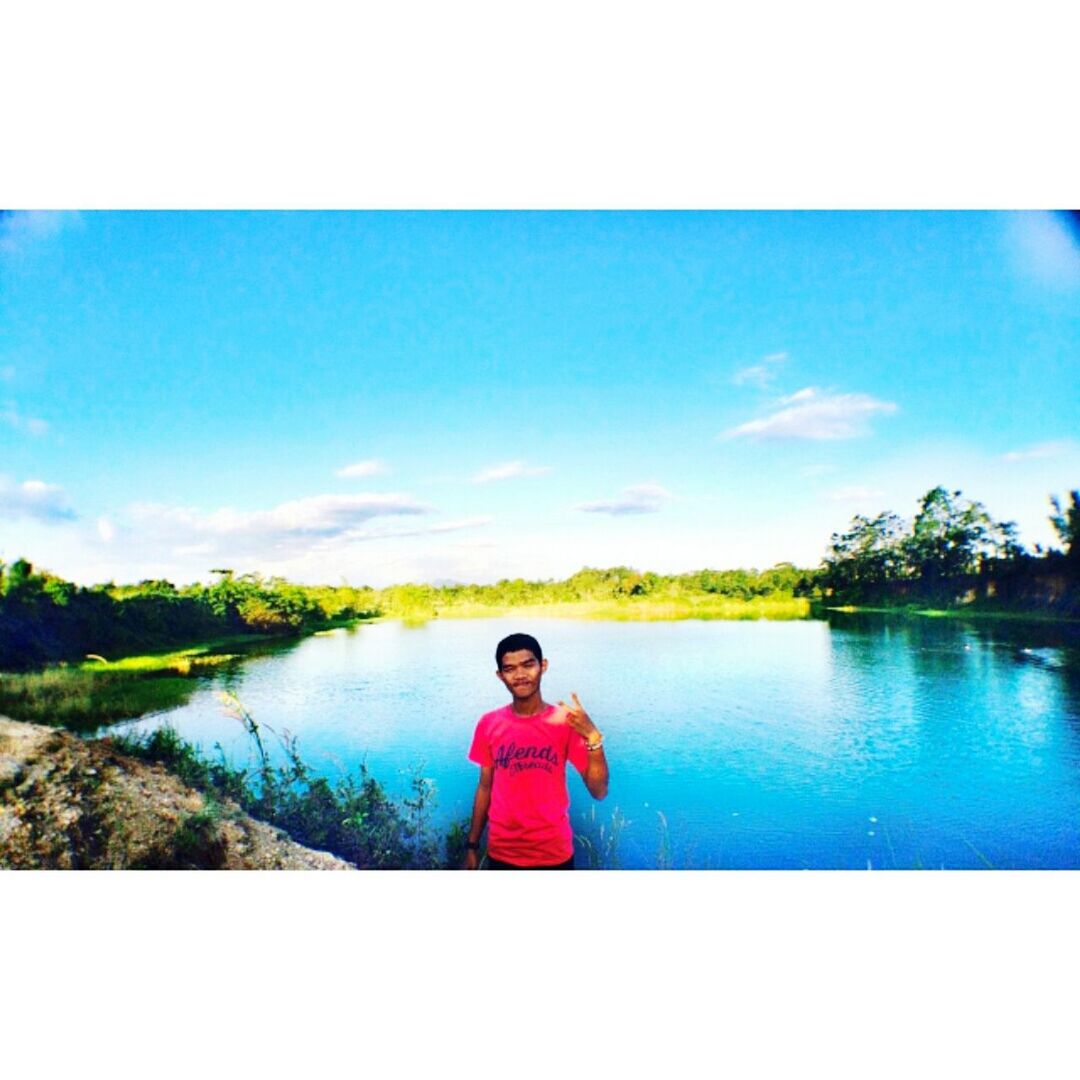 water, lifestyles, leisure activity, sky, childhood, auto post production filter, rear view, person, casual clothing, tranquility, standing, lake, blue, tranquil scene, scenics, sitting, nature, beauty in nature