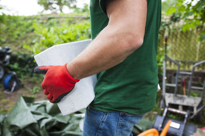 Midsection of male worker carrying stone in garden