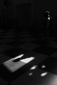 Shadow of man walking on tiled floor