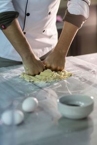 Midsection of chef kneading dough in kitchen