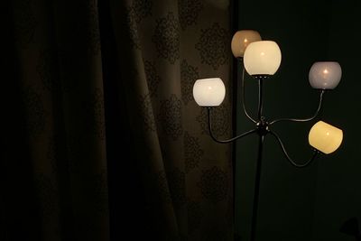 Close-up of illuminated lamp hanging against wall