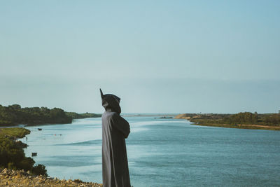 Rear view of man looking at sea against sky