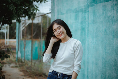Beautiful young woman standing against wall