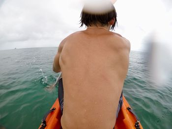 Rear view of shirtless man in sea against sky