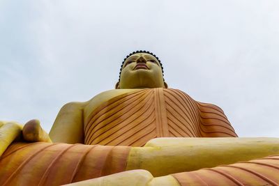 Low angle view of buddha statue against sky