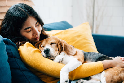 Young woman with dog lying on sofa at home