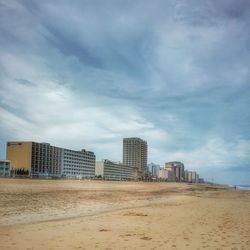 Beach by city against sky