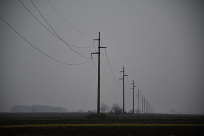 Low angle view of electricity pylon on field against sky