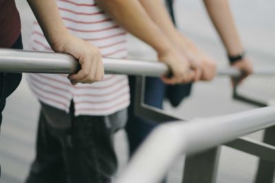 Midsection of people holding railing