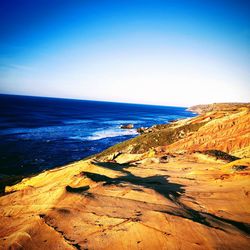 Scenic view of beach against clear blue sky