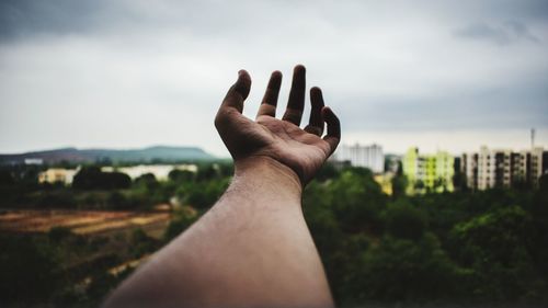 Close-up of human hand against sky