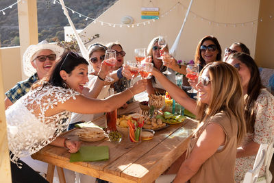 Women toasting drinks while sitting at table