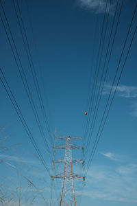 Low angle view of electricity pylon against blue sky