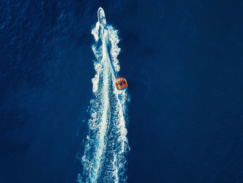 Aerial view of a watersports speedboat and people having fun while riding on a floating sofa.