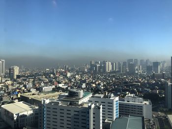 High angle view of buildings in city against blue sky