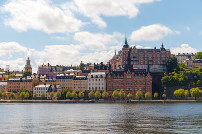 Buildings by river against sky