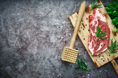 Raw beef steak with tomato, garlic, pepper, salt and rosemary on frying pan on a dark background.