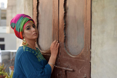 Beautiful young woman standing against building